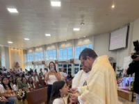 A catequisanda Laura Calderan recebendo pela primeira vez a Eucaristia